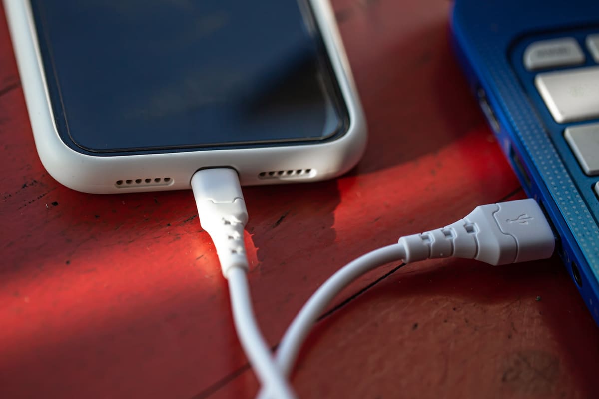 A smartphone connected to a laptop with a USB cable for backing up