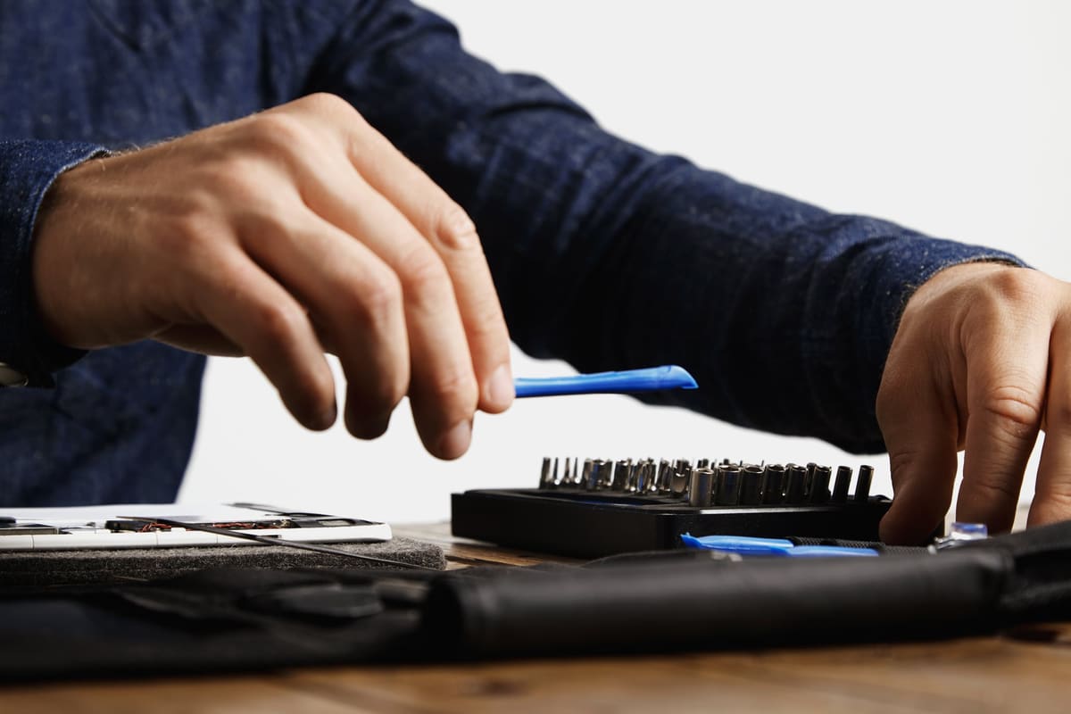 A technician using a plastic opening tool to repair a tablet
